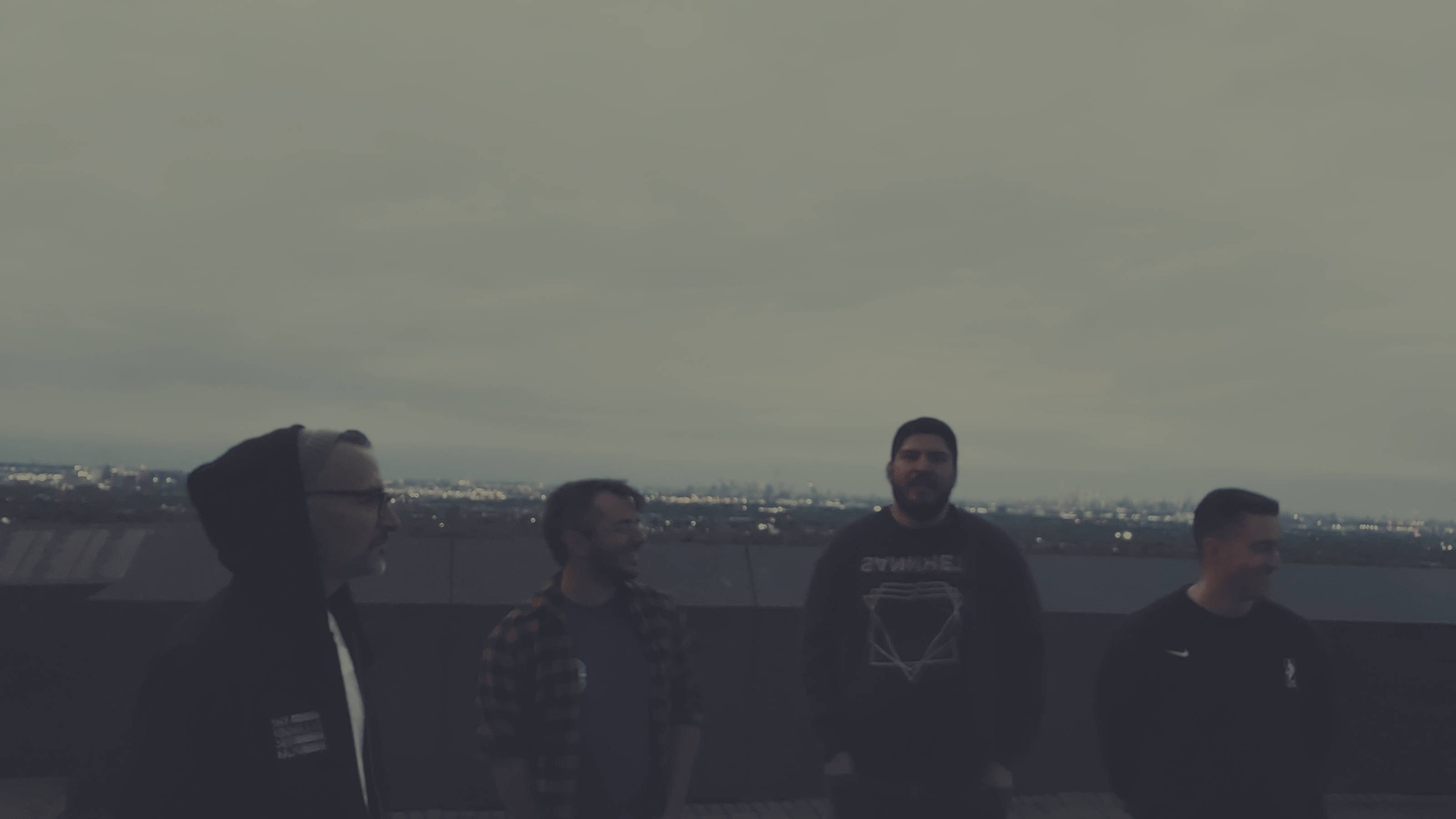 Negative Bliss members look away in front of a city skyline while Jonathan Hernandez looks ahead